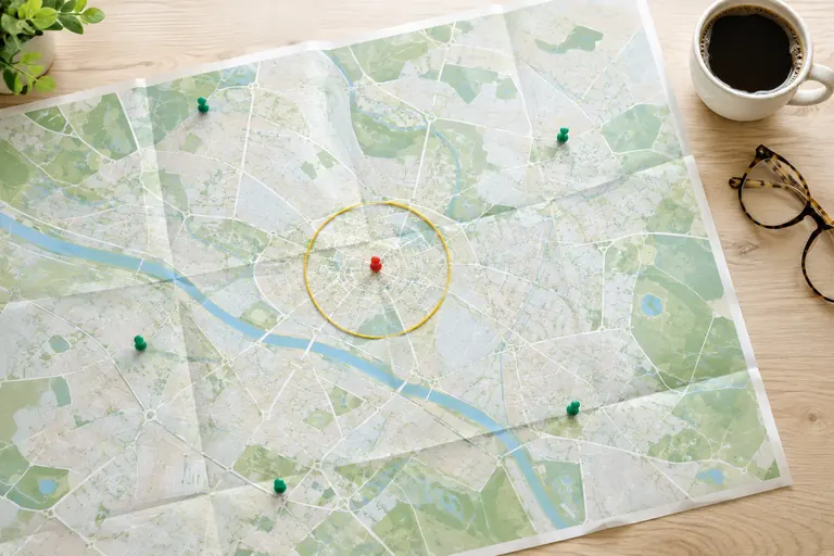 Carte papier avec épingles vertes et rouge entourées d’un fil jaune délimitant une zone