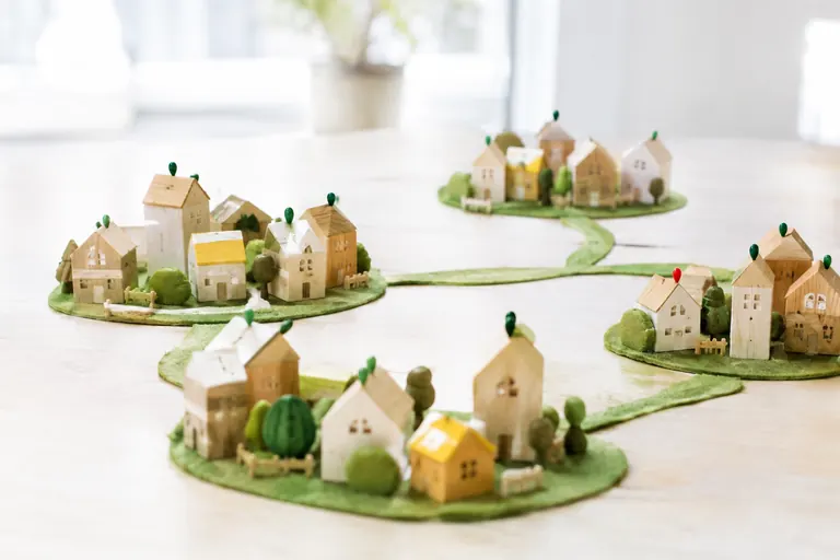 Maquettes de maisons en bois regroupées en villages reliés par des chemins verts